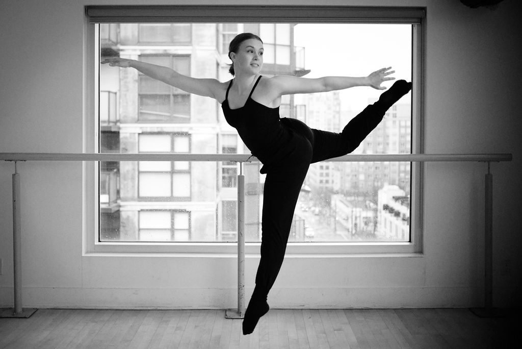Black and white ballet portrait at the barre in a dance studio