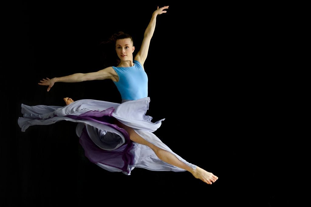 Dancer leaping in costume, photographed against a black studio backdrop