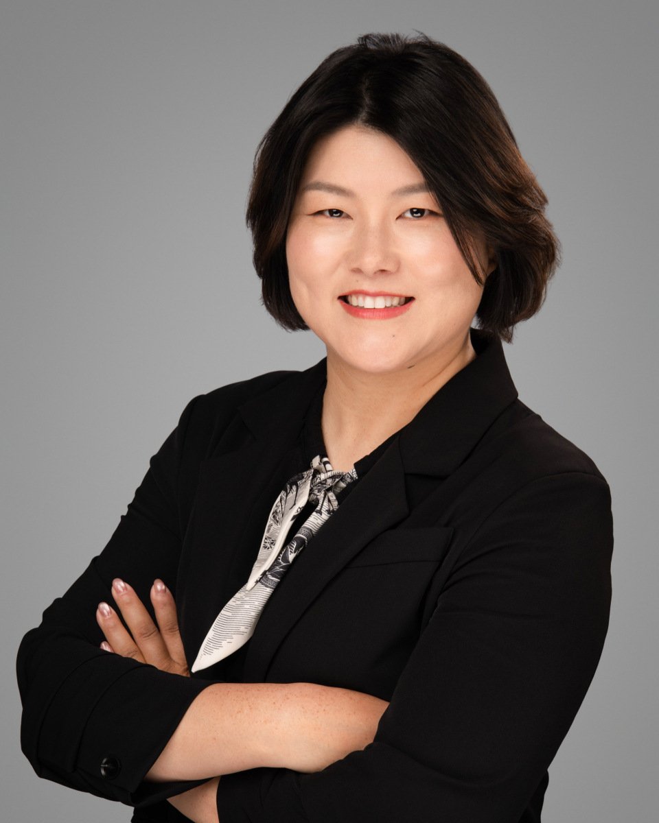 Conference headshot of a woman in a black blazer and patterned scarf