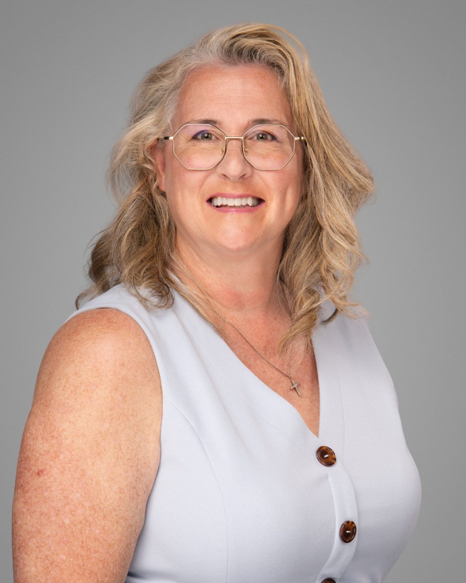 Conference headshot of a blonde woman in glasses and a pale sleeveless top