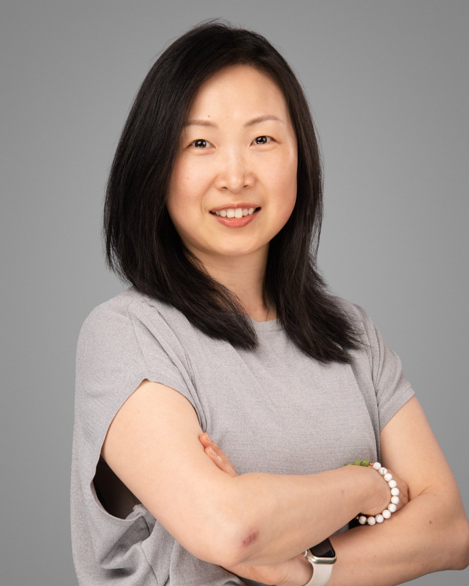 Conference headshot of a woman in a grey tee with arms crossed