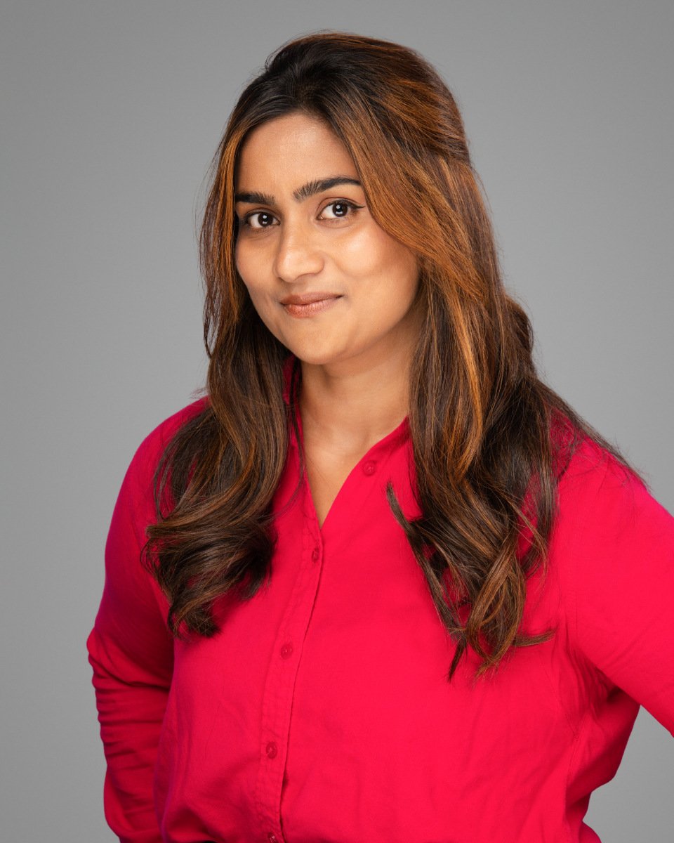 Conference headshot of a woman in a red shirt with long wavy hair