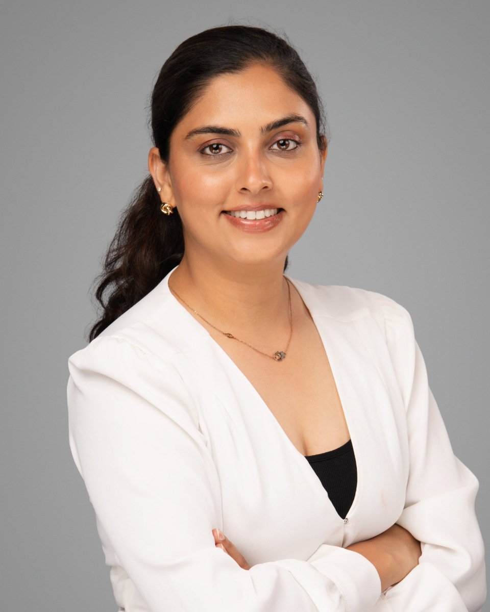Conference headshot of a woman in a white blazer on a grey backdrop