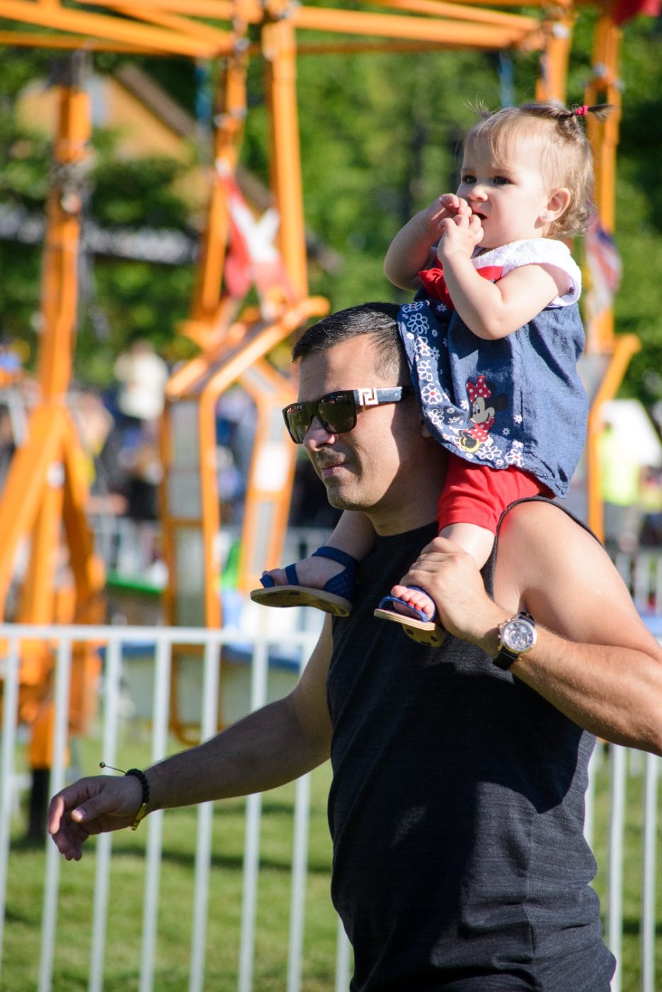 Father carrying his daughter on his shoulders through the crowd at a Canada Day celebration