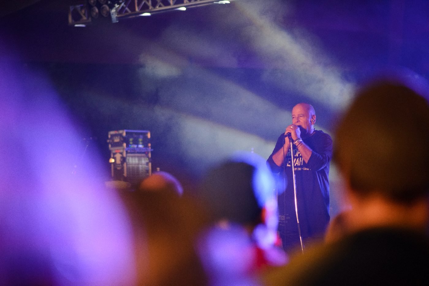 Singer at the microphone under hazy blue stage lighting, photographed from within the festival crowd
