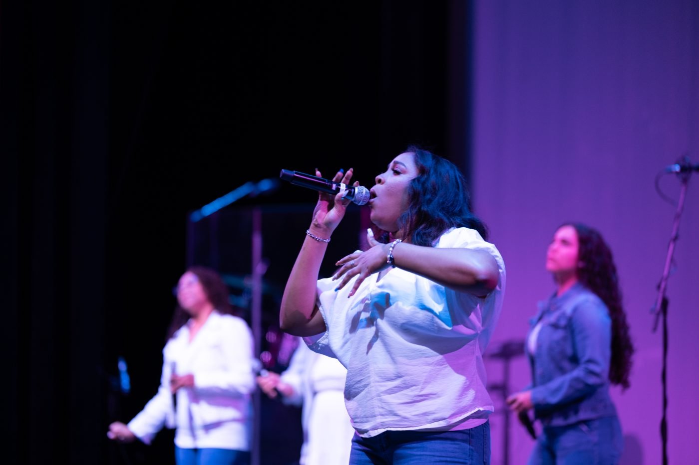 Concert photographer&rsquo;s frame of a vocalist singing into the microphone under purple stage lights