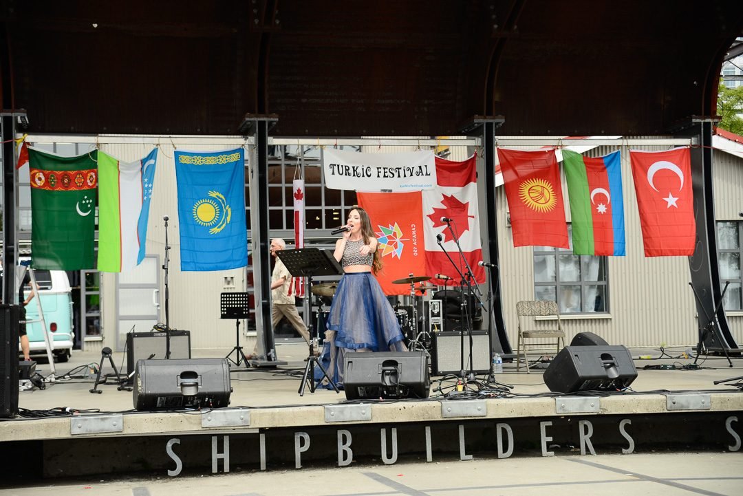 Dancers performing on a cultural festival stage lined with national flags
