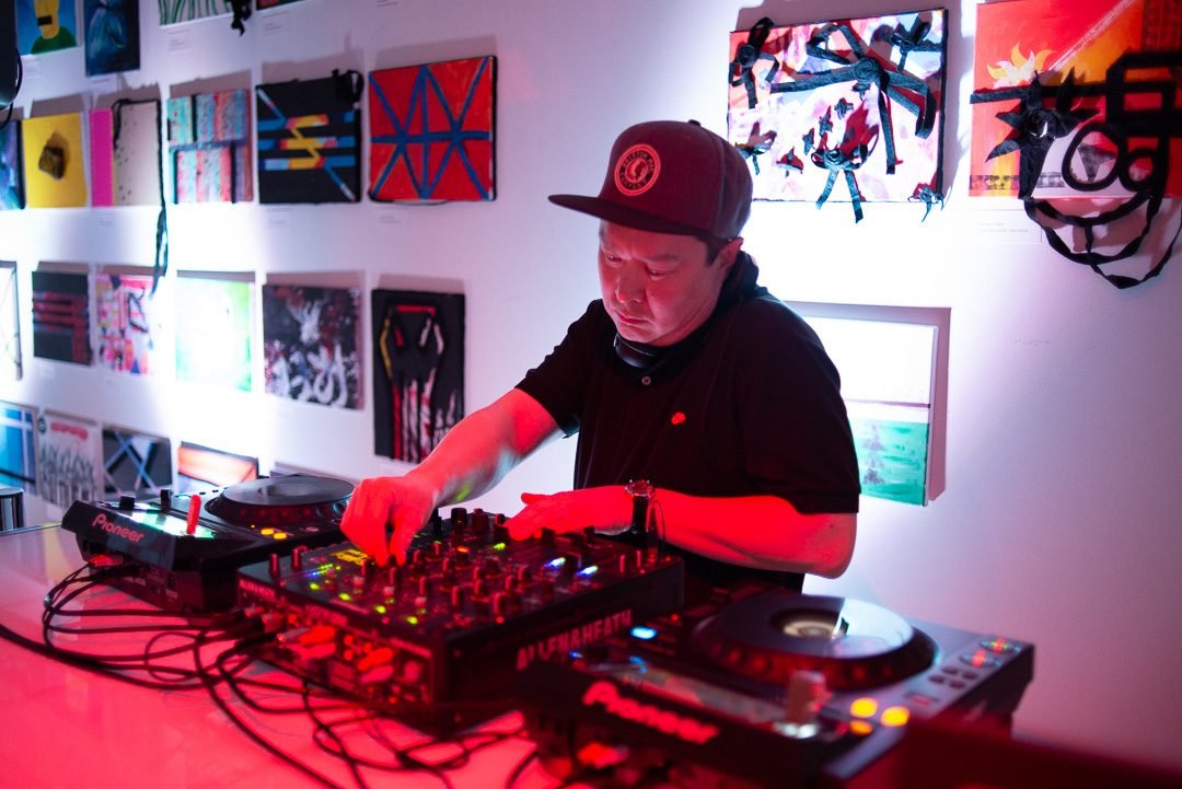 DJ playing a set under red lighting at a late night gallery event in Vancouver