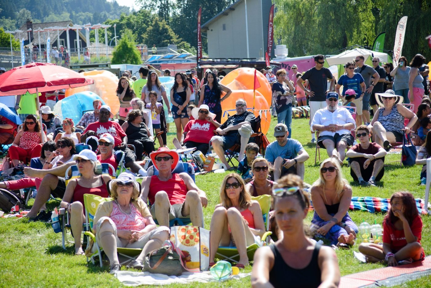 Festival audience seated on the lawn under umbrellas watching the main stage