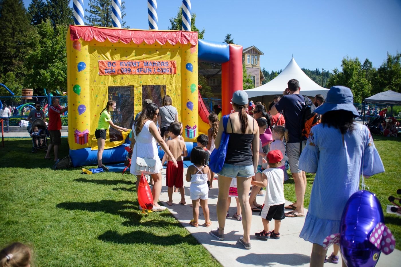 Children queuing for the bouncy castle in the kids zone at a community festival