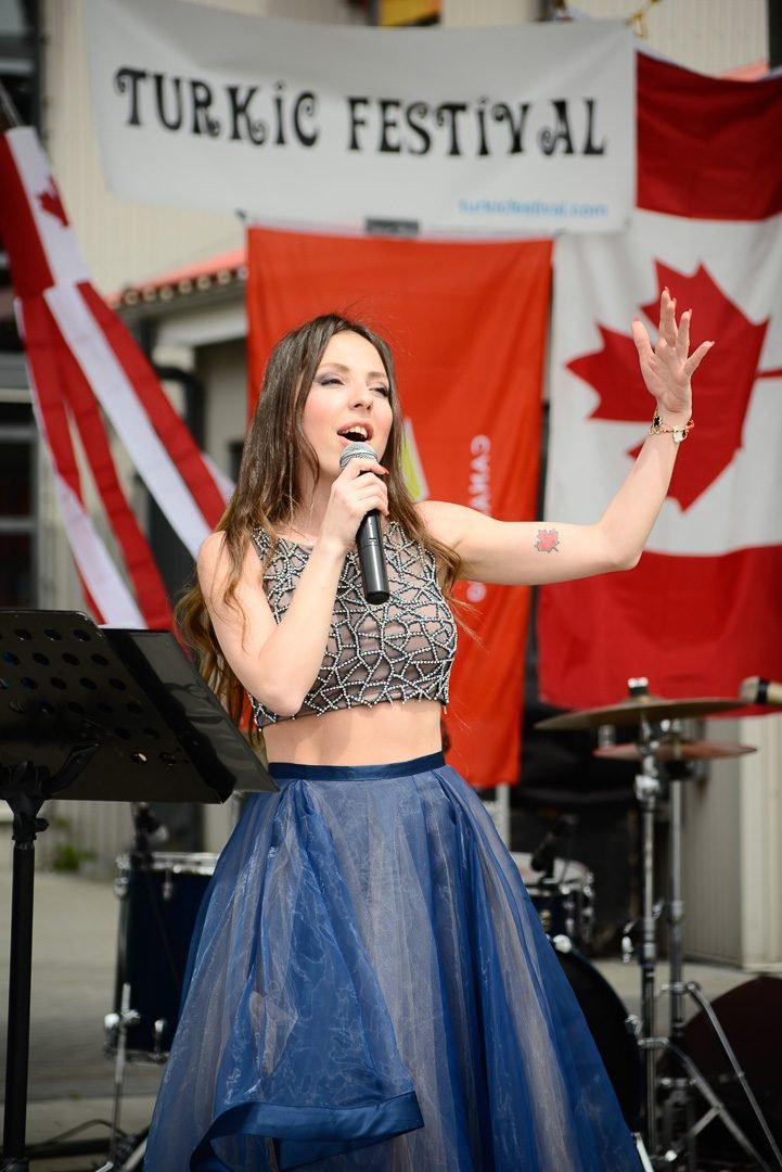 Singer performing with a live band on an outdoor festival stage in downtown Vancouver