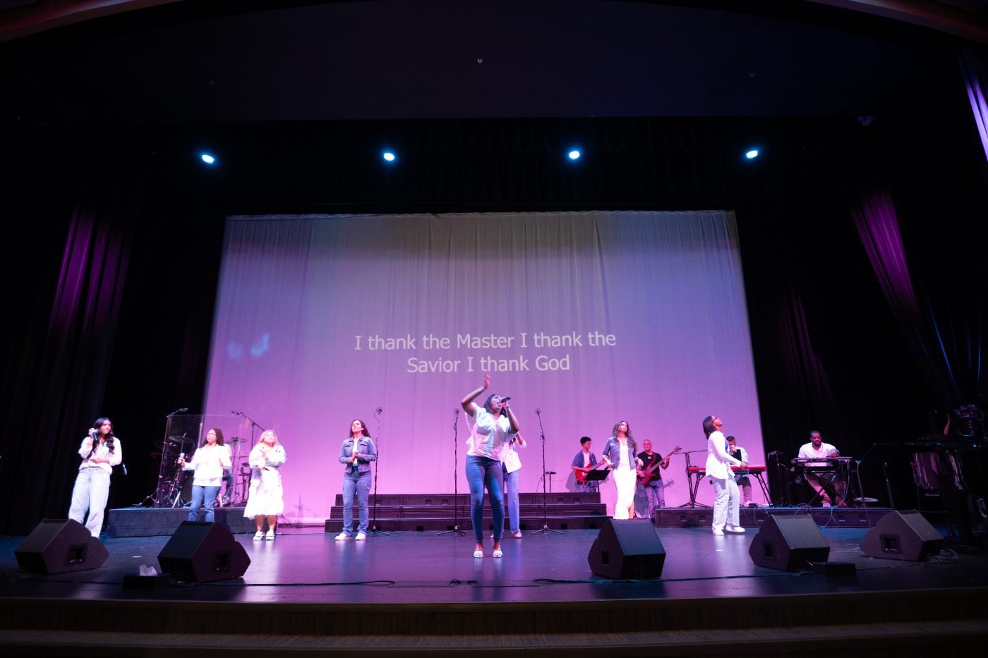 Full band and choir performing under purple stage lighting at a gospel concert in Vancouver