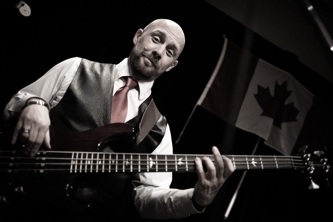 Black and white photograph of a bassist performing at a live music event