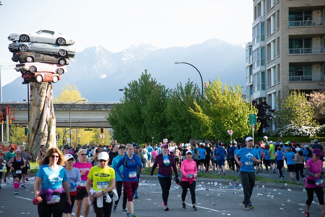 Field of marathon runners on the course with the North Shore mountains behind them