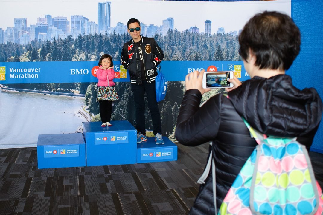 Participants posing on a branded podium in front of a city skyline backdrop at a race expo