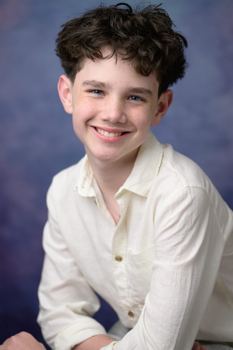 Young actor headshot photographed on a painted blue backdrop