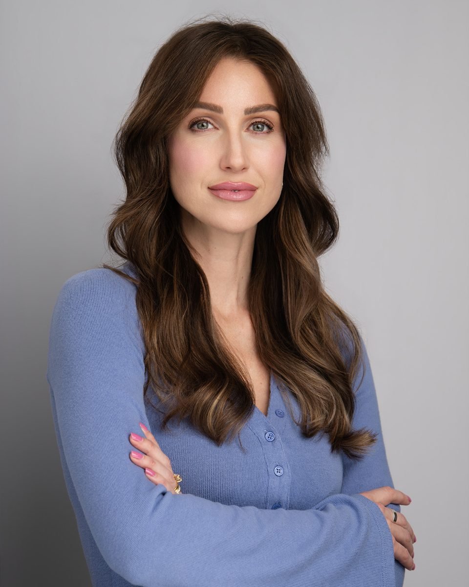 Studio headshot of a woman in a blue cardigan on a grey backdrop at the Langley studio