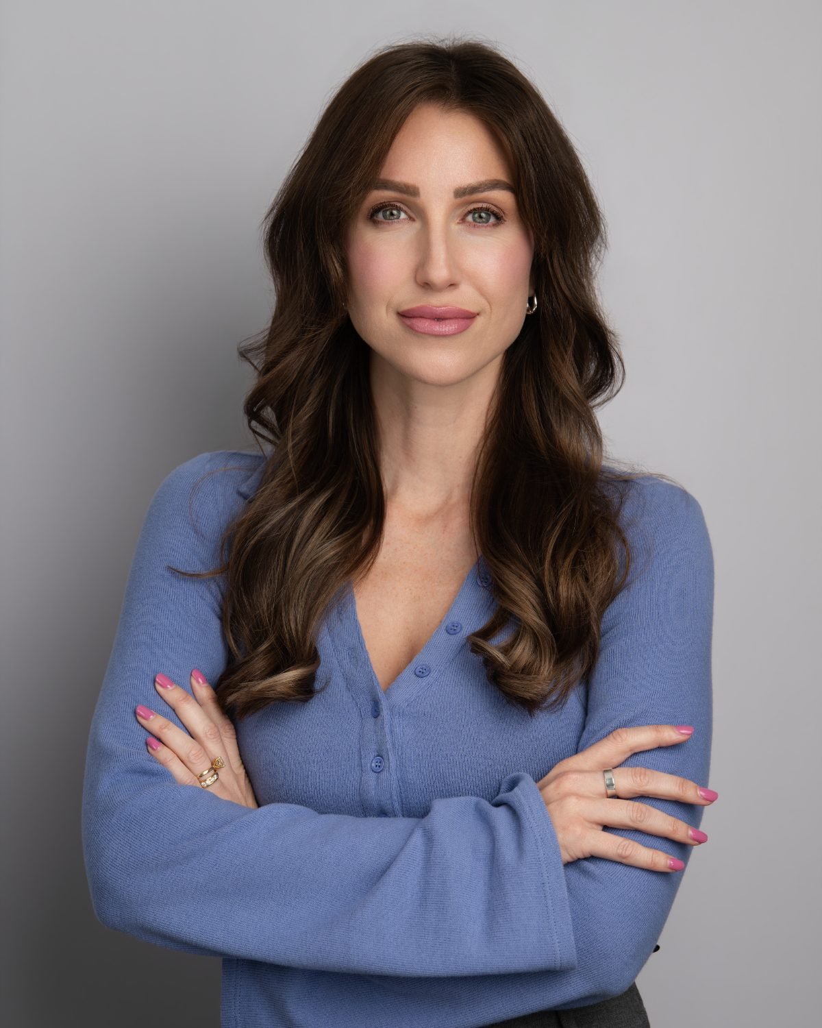 On-site headshot of Leighann in a blue sweater photographed at her office on a grey backdrop