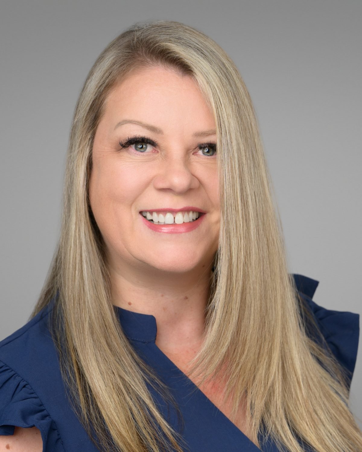 On-site headshot of Lina Lilley photographed on a grey backdrop at her workplace