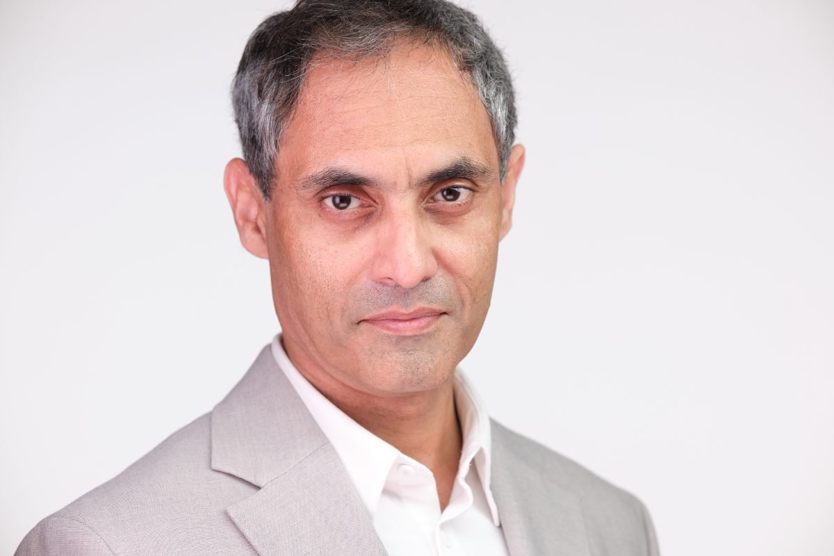 Professional headshot of Saqib Khan on a light grey studio backdrop