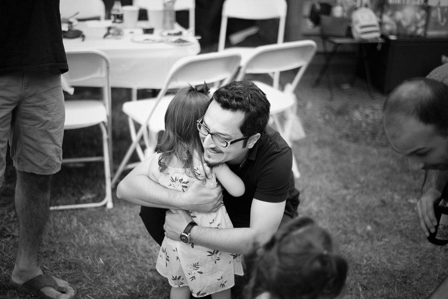 Black and white candid of two guests hugging at a backyard celebration
