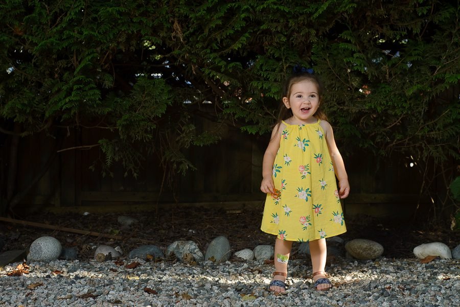 Birthday girl in a yellow dress standing in the garden at her party