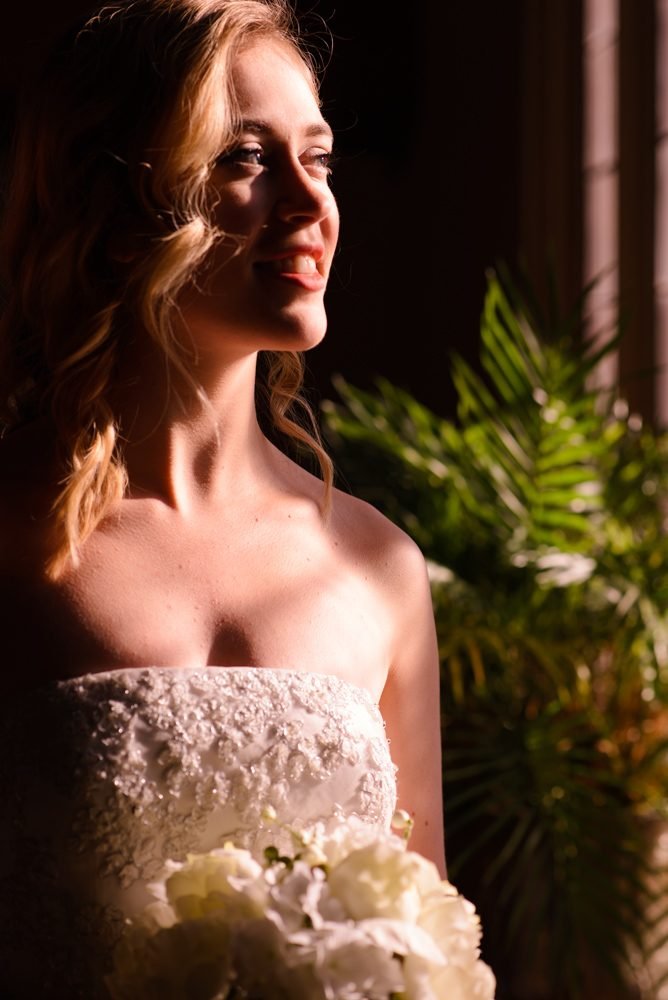 Bride portrait in soft window light holding a white hydrangea bouquet before the ceremony