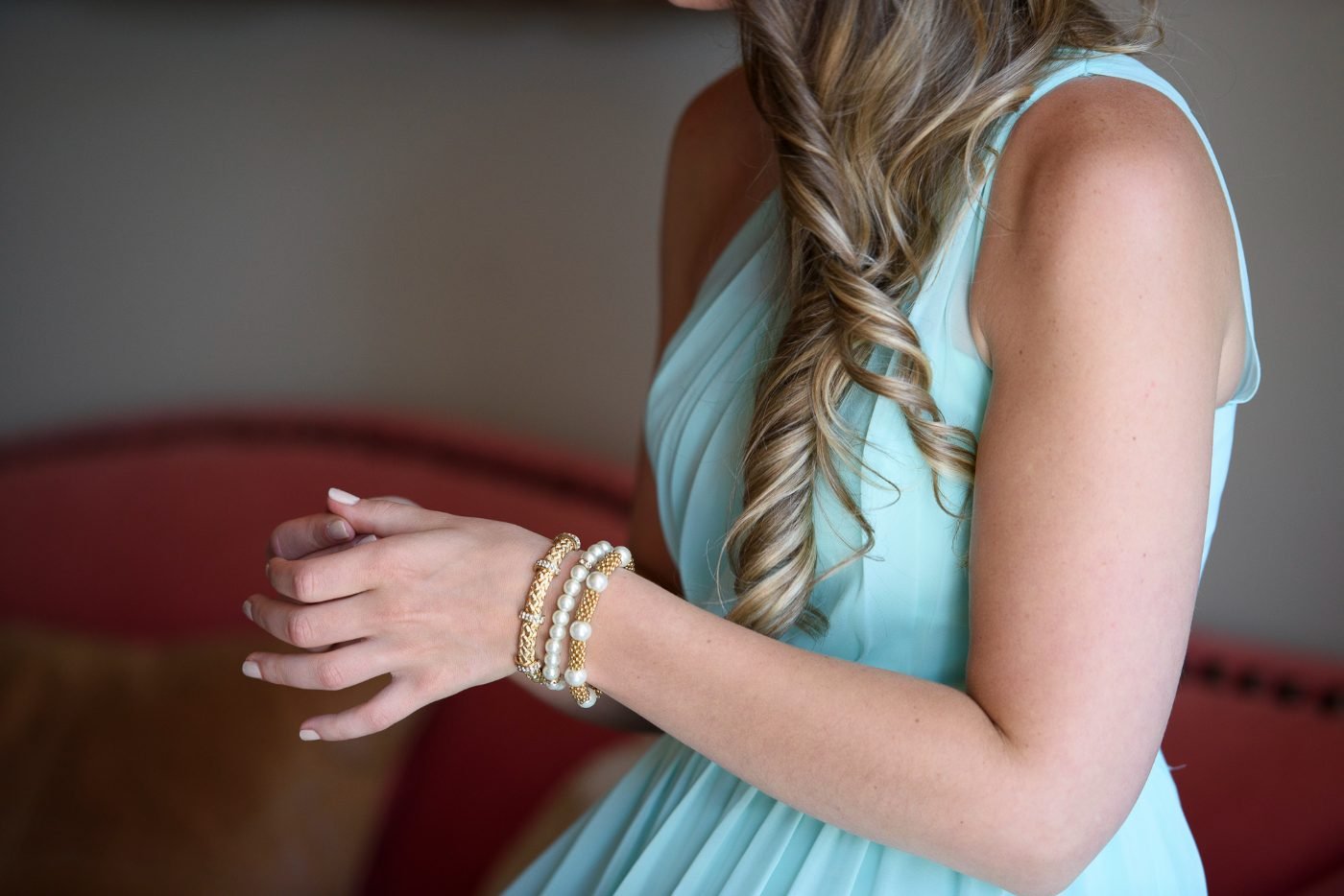 Getting ready detail of a bridesmaid in a mint dress with pearl and gold bracelets before the wedding