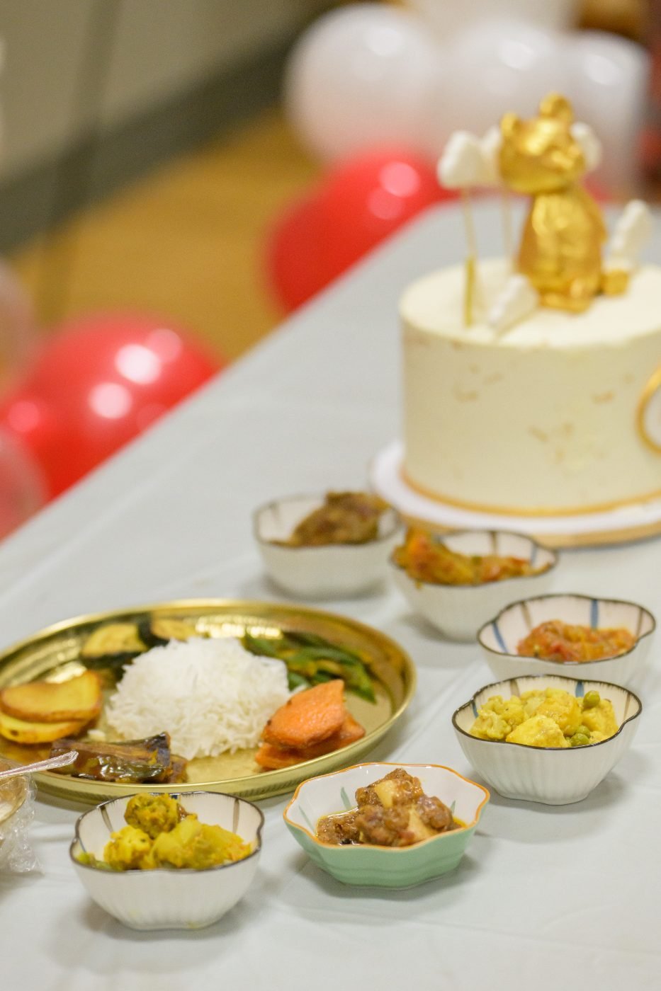 Celebration cake surrounded by bowls of traditional food photographed before the guests are served