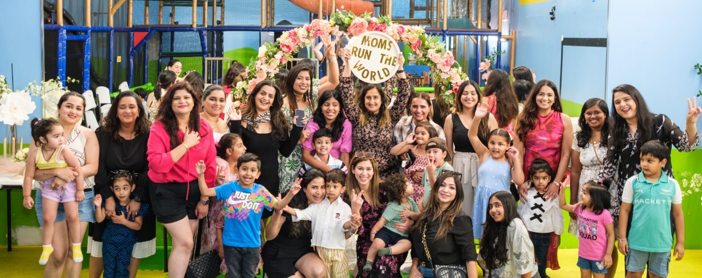 Wide group photo of every guest at a family celebration, gathered around a floral backdrop