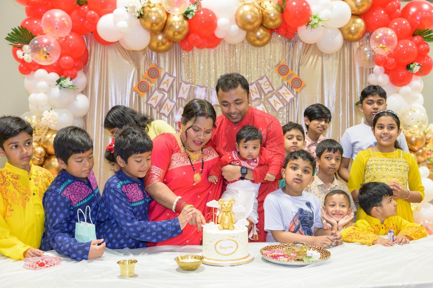 Extended family gathered around the cake table for a group photo at a cultural celebration