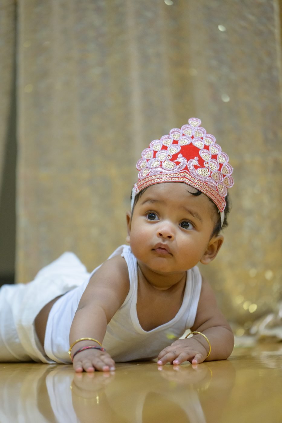 Baby wearing a paper crown crawling towards the camera at her first birthday party
