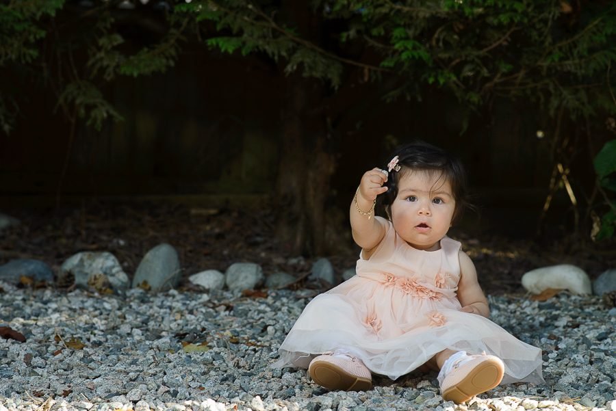 First birthday portrait of a baby in a tulle dress sitting outdoors at her party