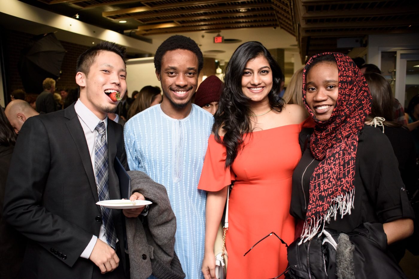 Four friends laughing together at a graduation reception after the ceremony
