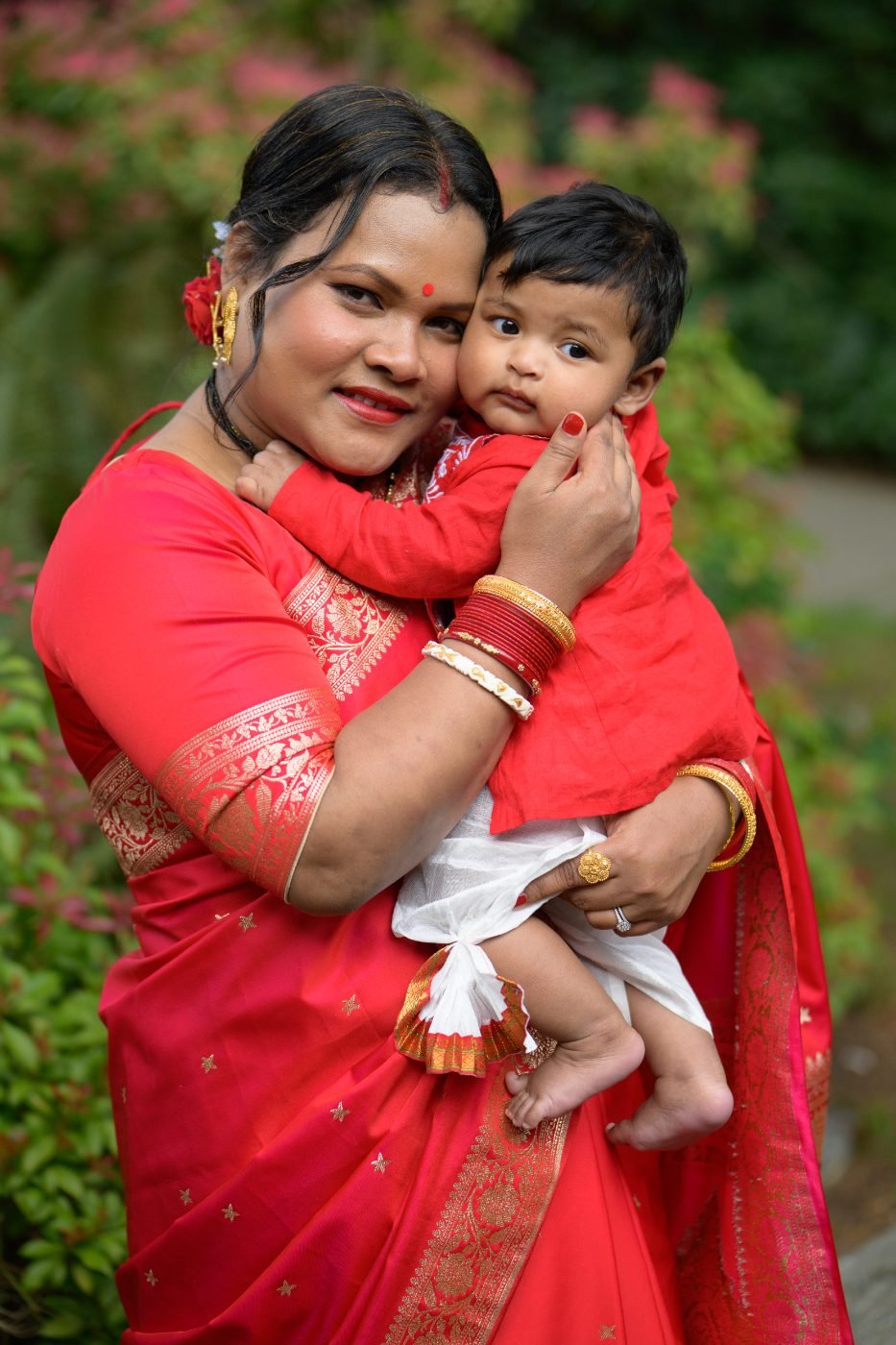 Mother in a red sari holding her baby at a family celebration in the Lower Mainland