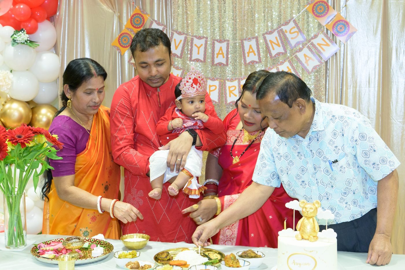 Parents and grandparents feeding a baby at a first rice ceremony family celebration