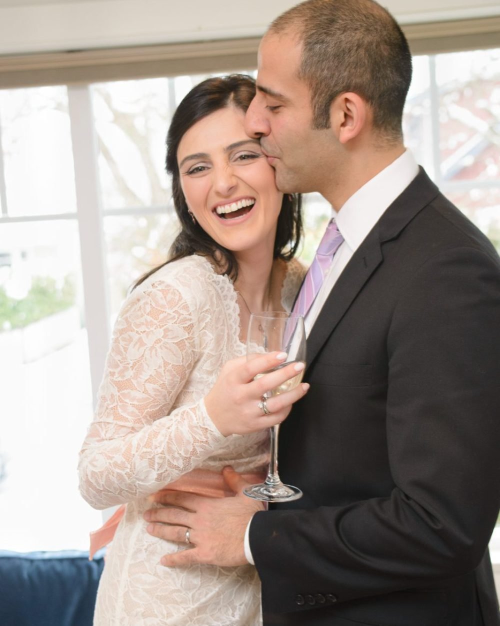Newlyweds laughing during a champagne toast at their reception