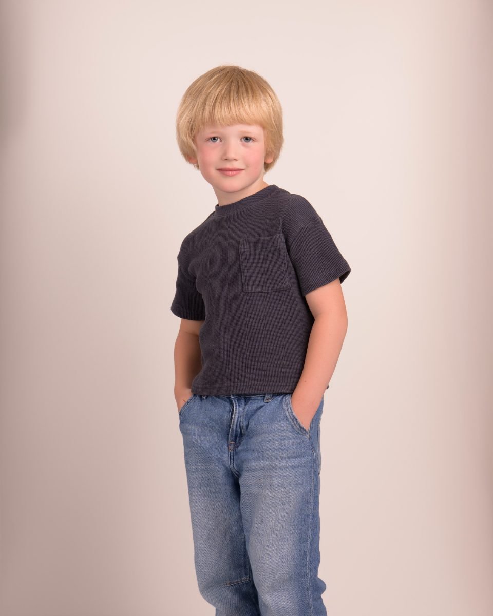 A boy in a navy tee and jeans photographed head to toe