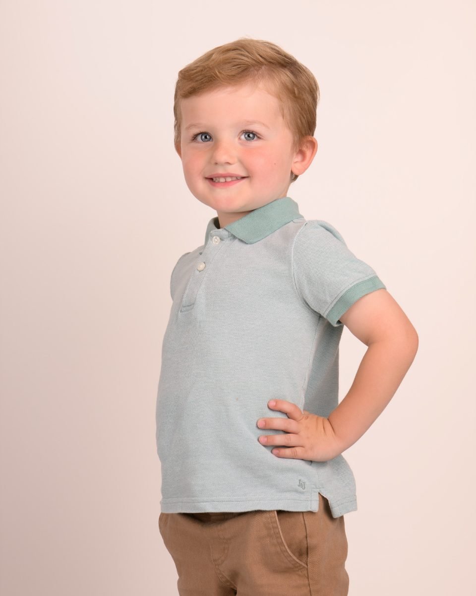 A boy in a mint polo with one hand on his hip
