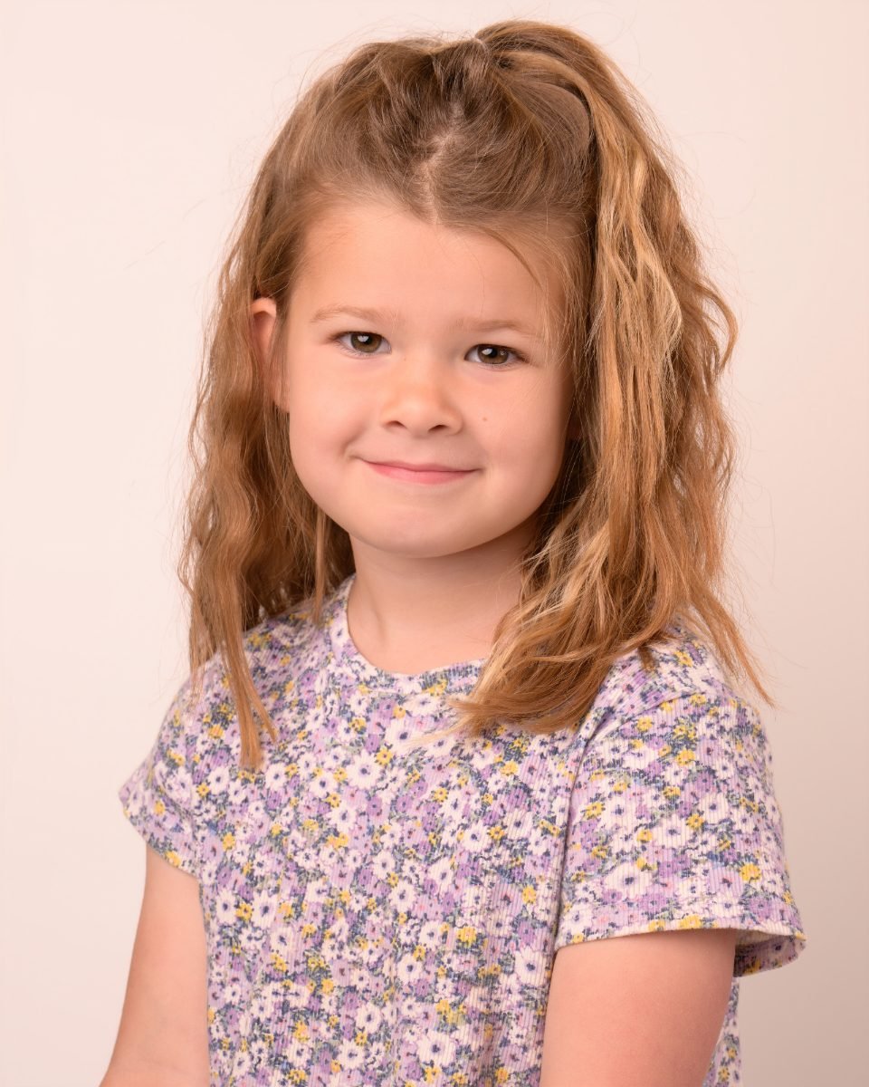 A girl with curly hair in a lilac floral top