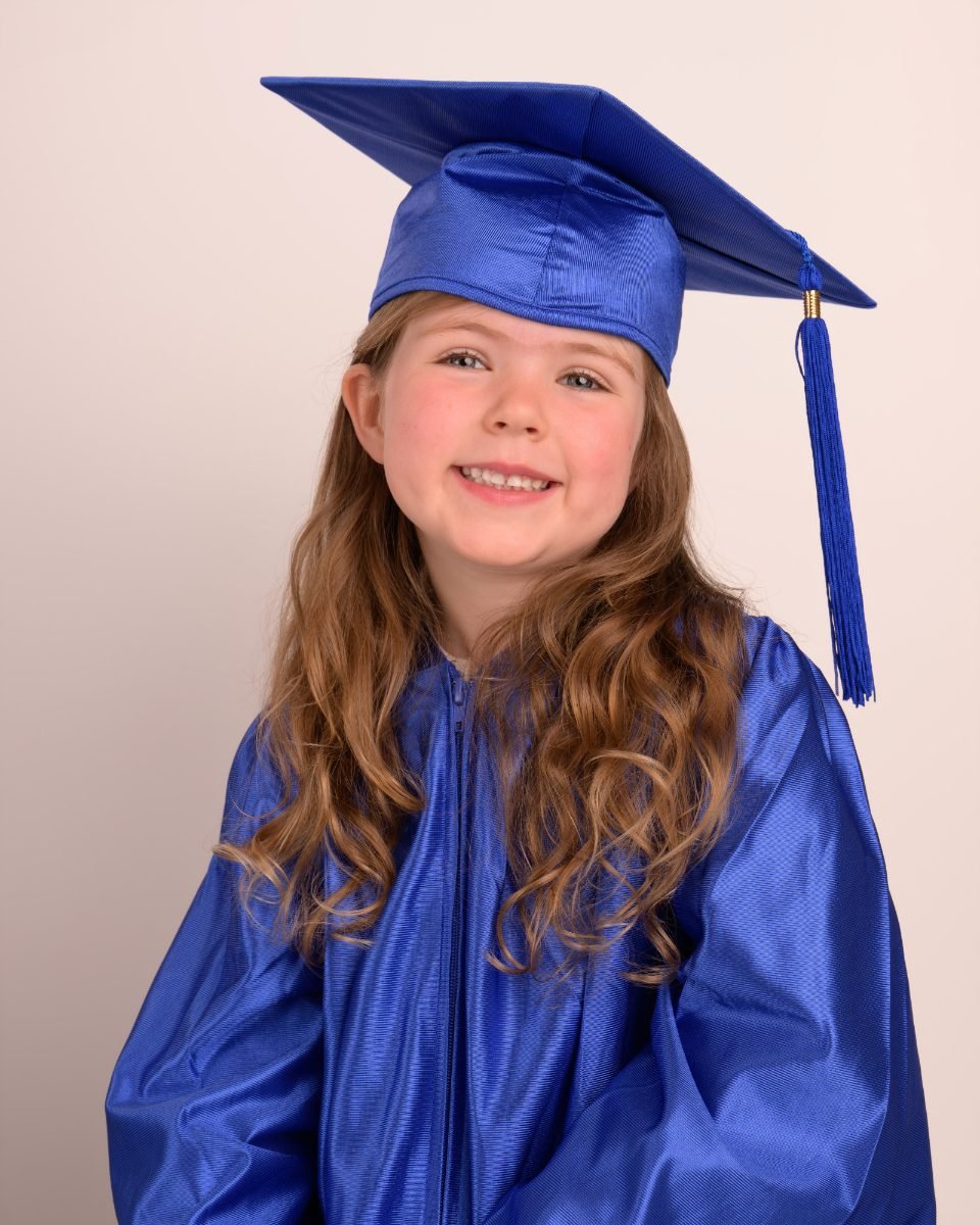 A preschool graduate in a royal blue cap and gown