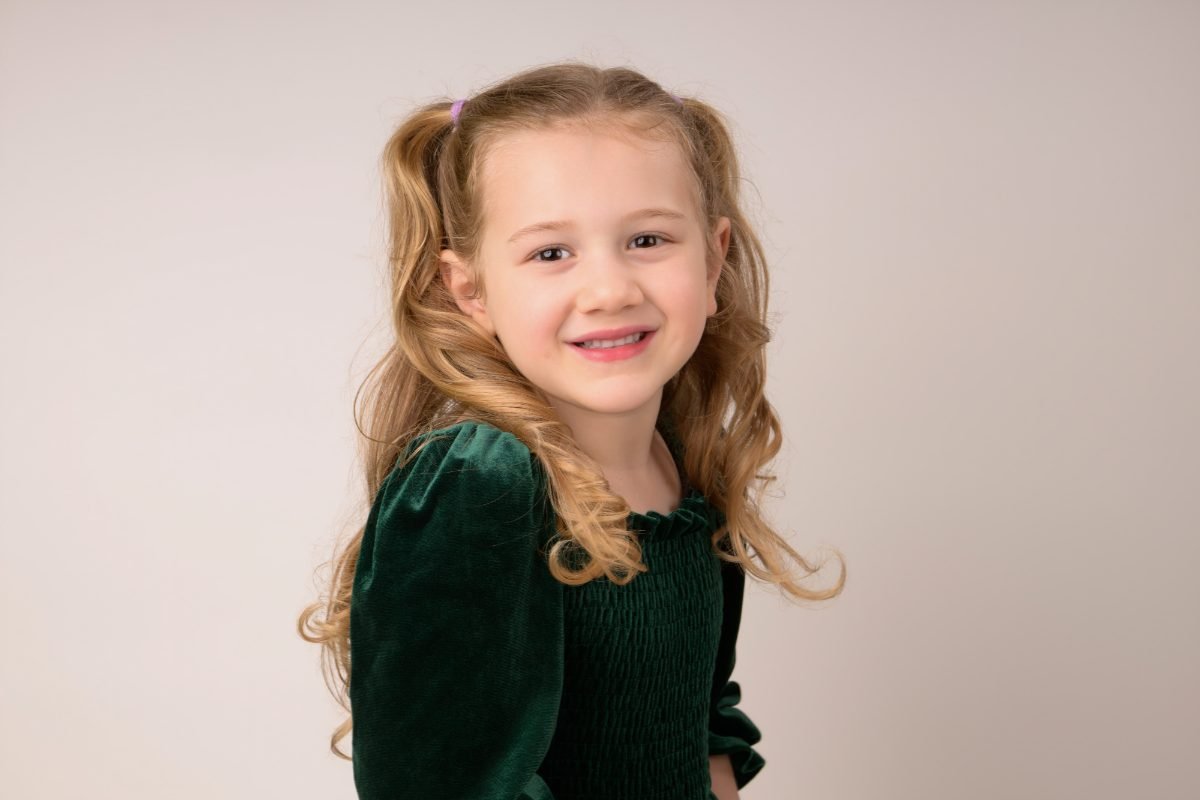 A girl in a green velvet dress glancing back over her shoulder