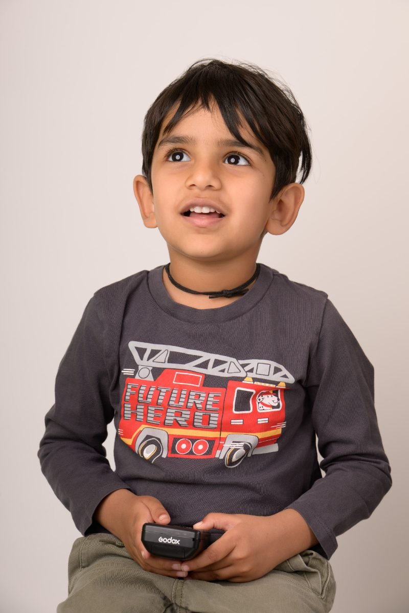 A boy in a fire-truck shirt holding a toy