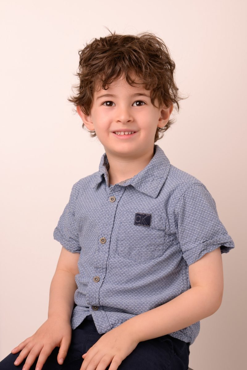 A boy with curly hair in a blue polo shirt