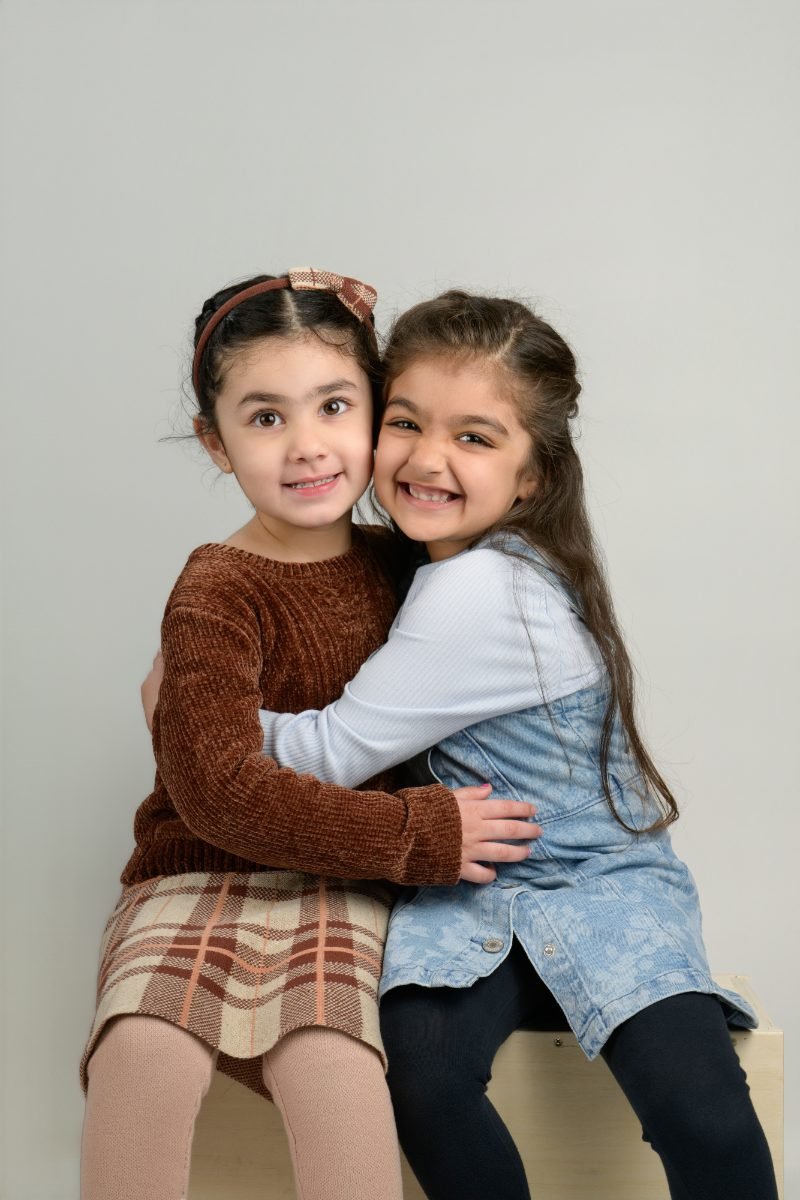 Two girls in a tight hug, both beaming at the camera
