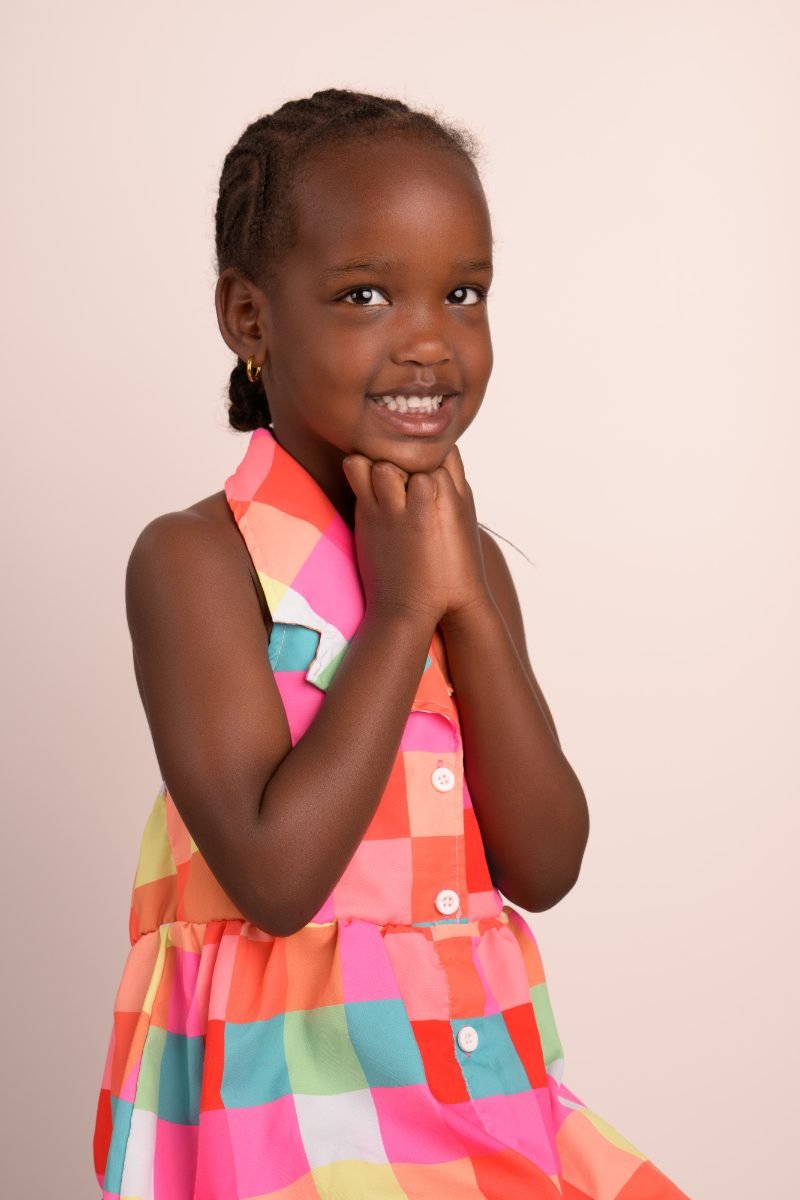 The same girl with a hand under her chin, grinning