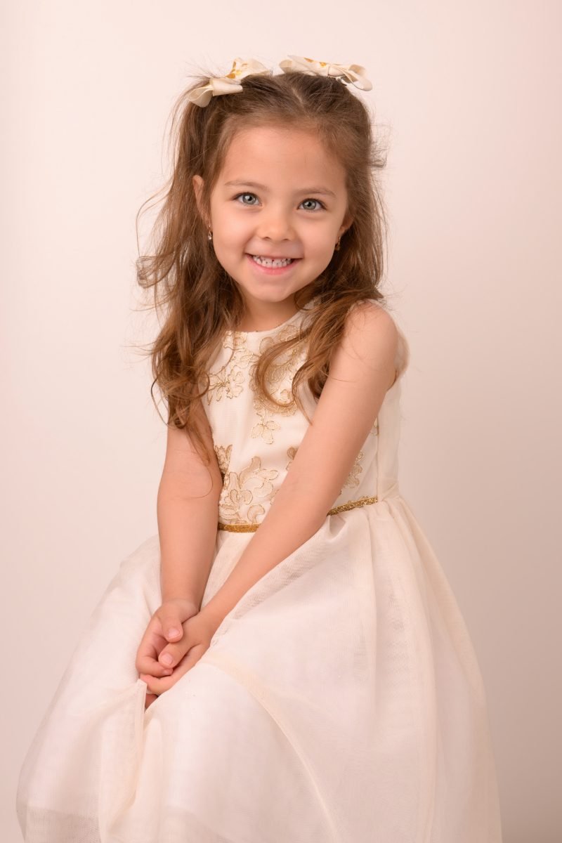 A girl in an ivory party dress with her hands together