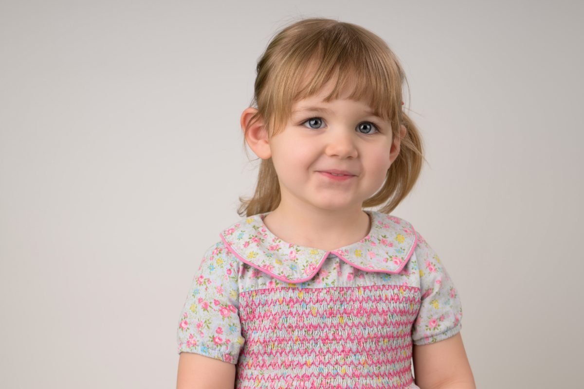A girl in a smocked floral dress on a soft grey backdrop