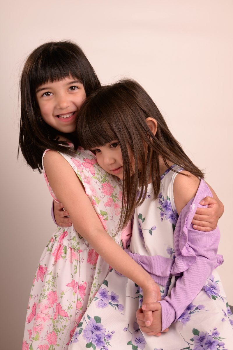 Two sisters in floral dresses hugging