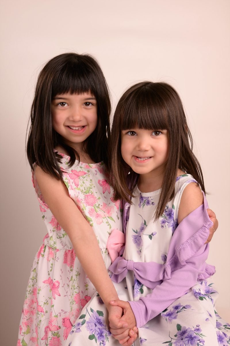 The same two sisters standing side by side, both smiling